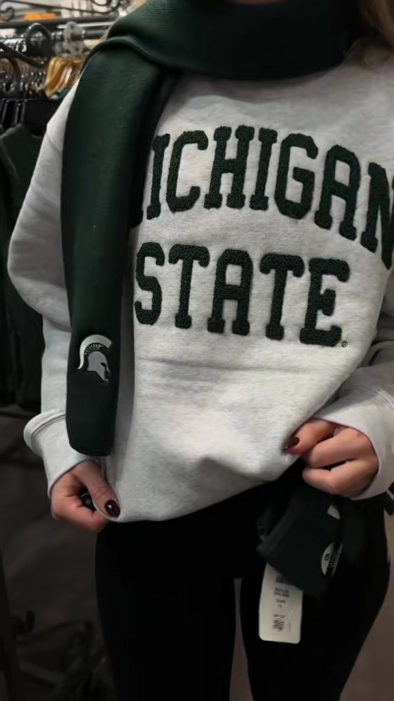 A student creator trying on a Michigan State sweatshirt